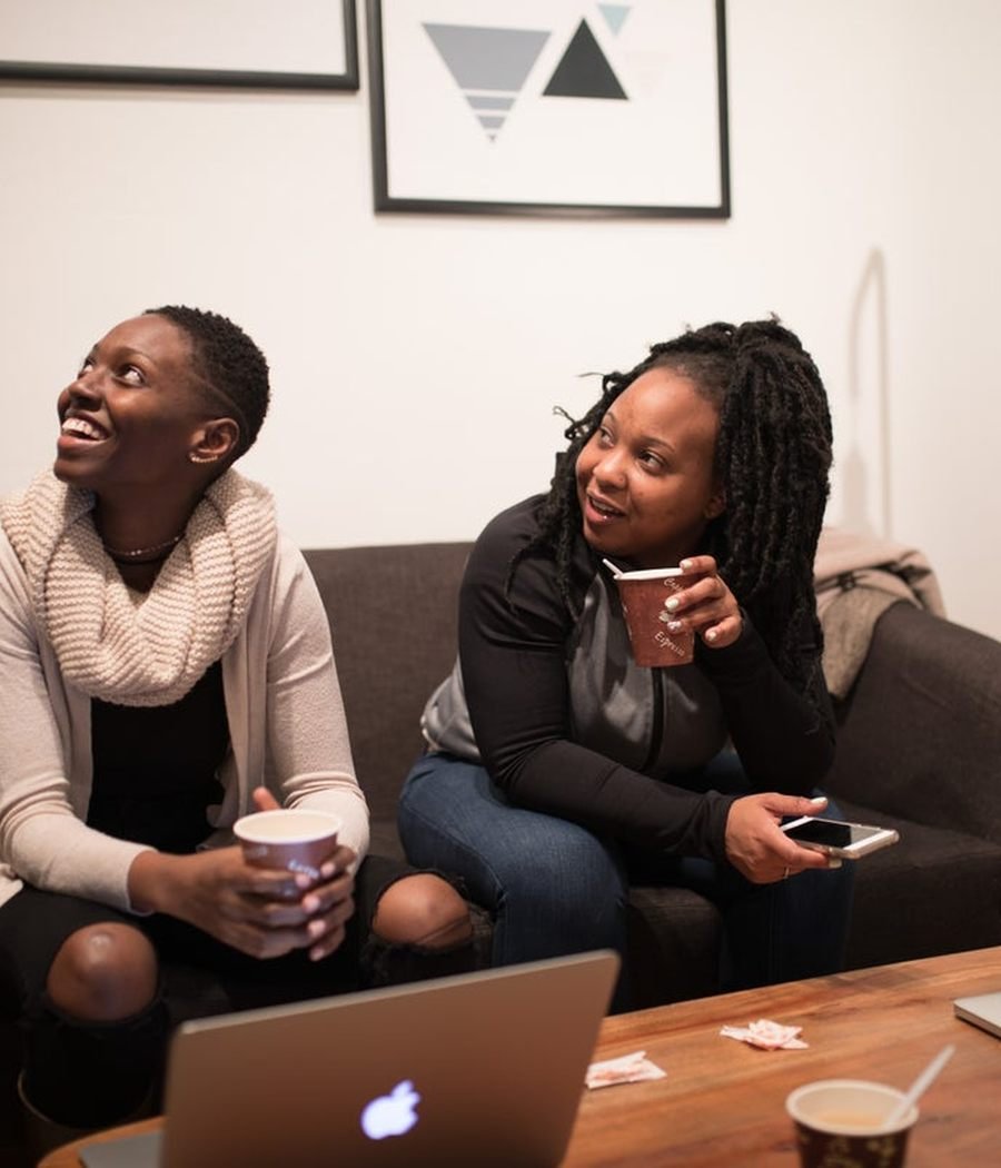 Two women sitting together on a sofa, laughing. Photo by a contributing Nappy photographer, CC0.