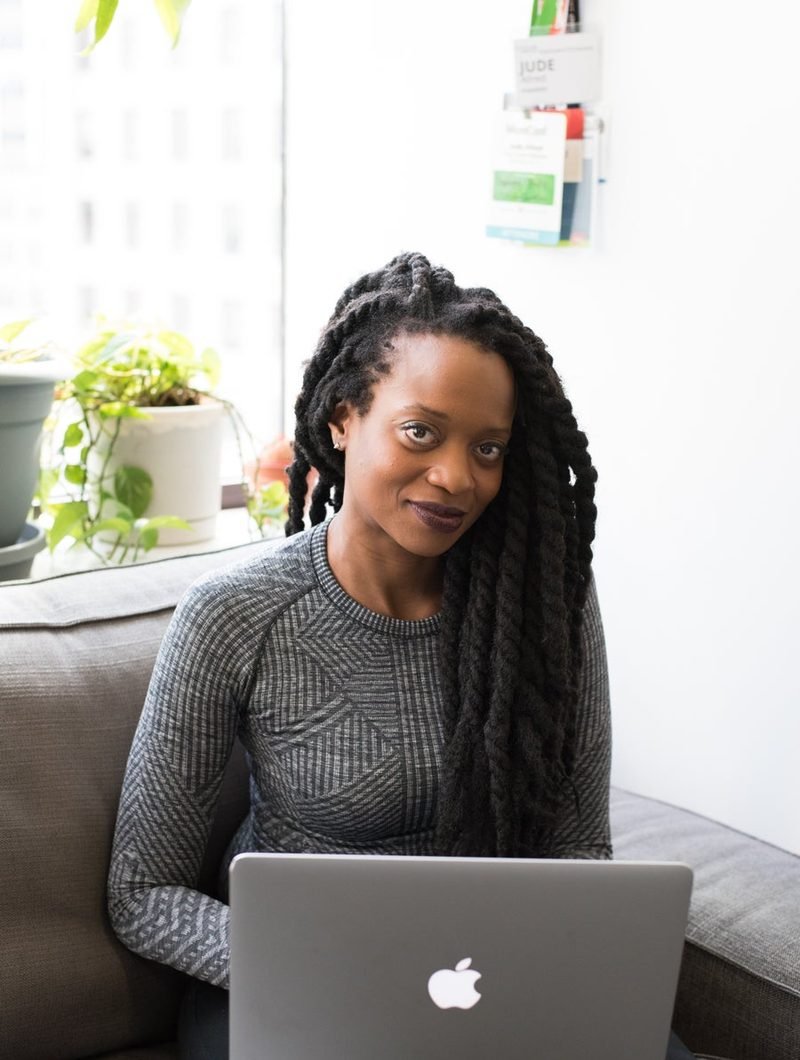 A woman working at a laptop by a window.
