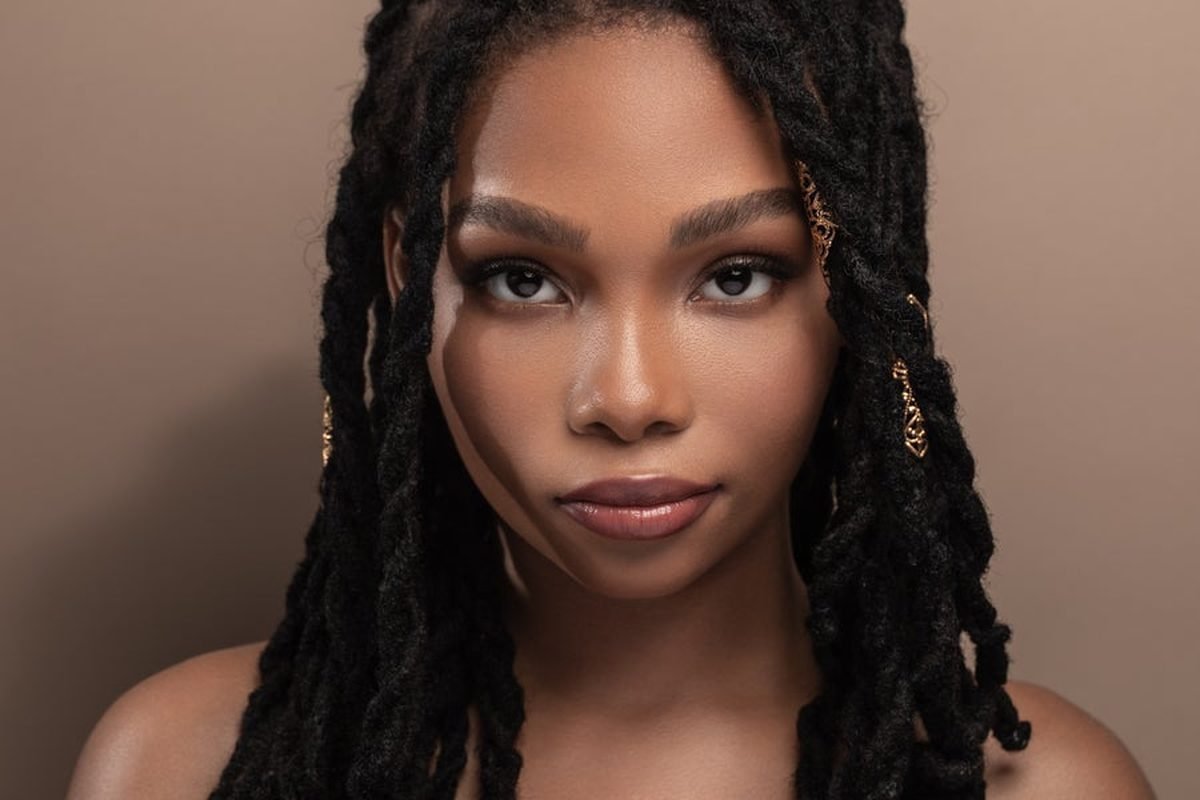 A woman with long locs looking directly at the camera.